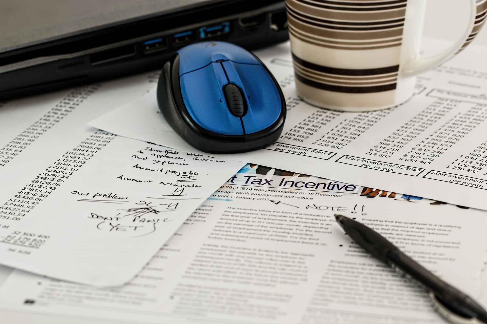 Blue computer mouse with a coffee cup and a black pen