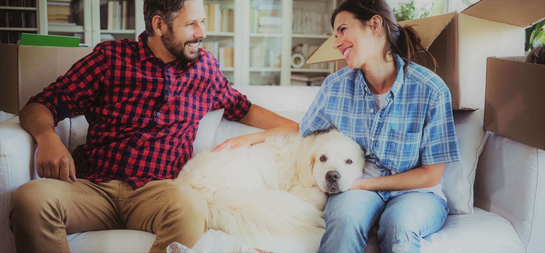 Husband and wife with a white dog surrounded by boxes