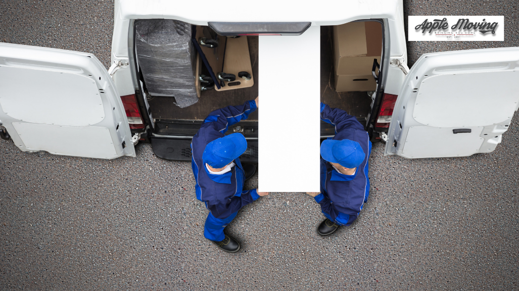 two movers lifting furniture inside mover van